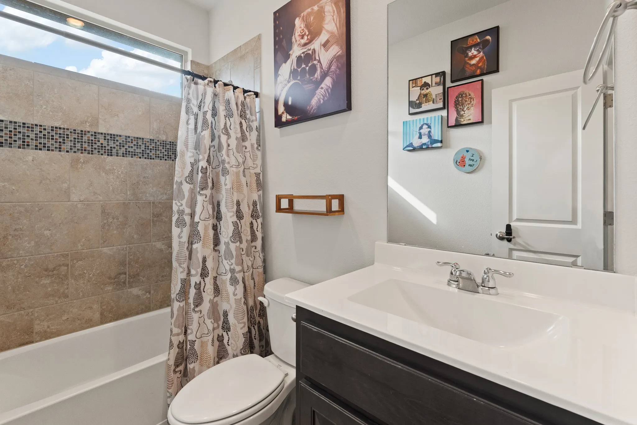 Bathtub with tile surround, mosaic accent band, and an elongated horizontal window
