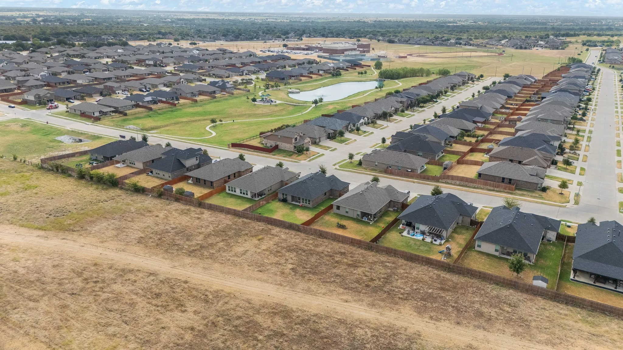 Master-planned community with a central pond and green spaces, featuring uniform rooflines and a cohesive architectural style