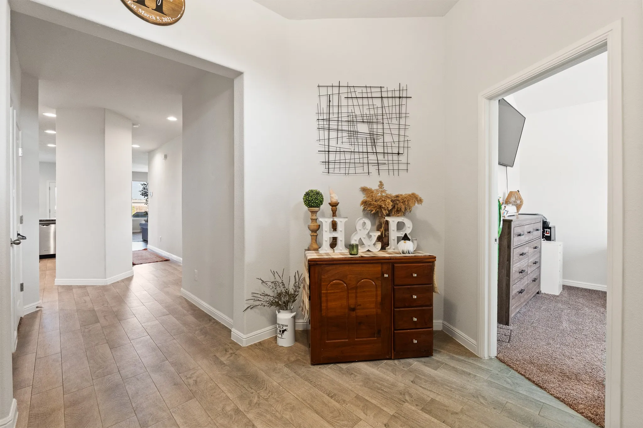 Light wood-finish flooring throughout, recessed ceiling lighting, and crisp white wall paint
