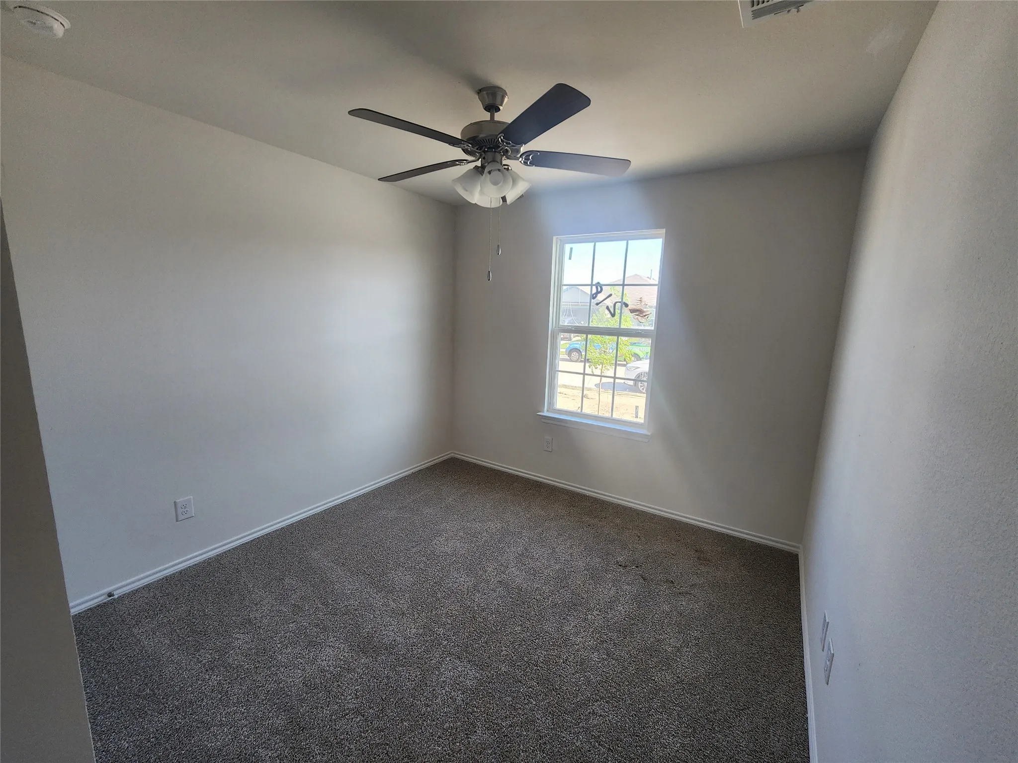 Carpeted flooring with a ceiling fan and a window