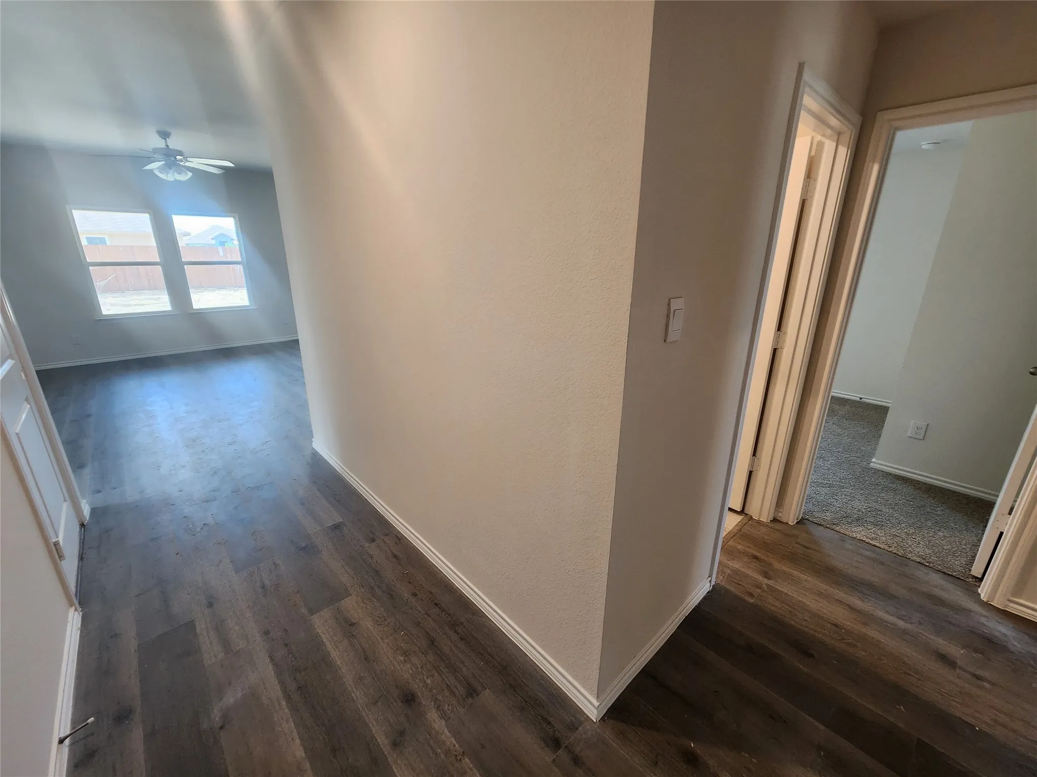 Wood-finish flooring throughout the main areas, with light gray carpeting in additional rooms