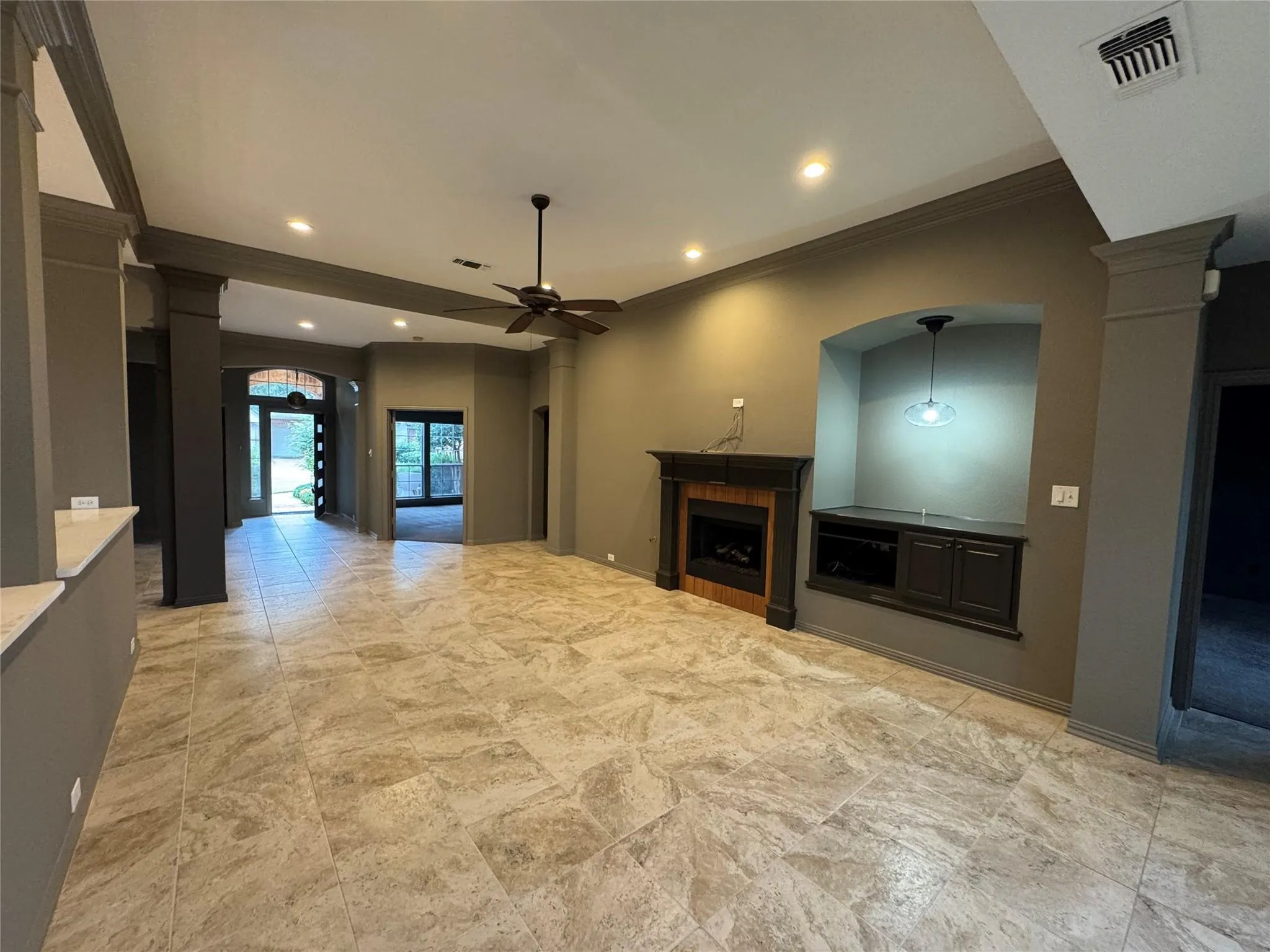 The living room, renovated kitchen, and breakfast area flow seamlessly together in a bright, open layout surrounded by walls of windows overlooking the backyard.