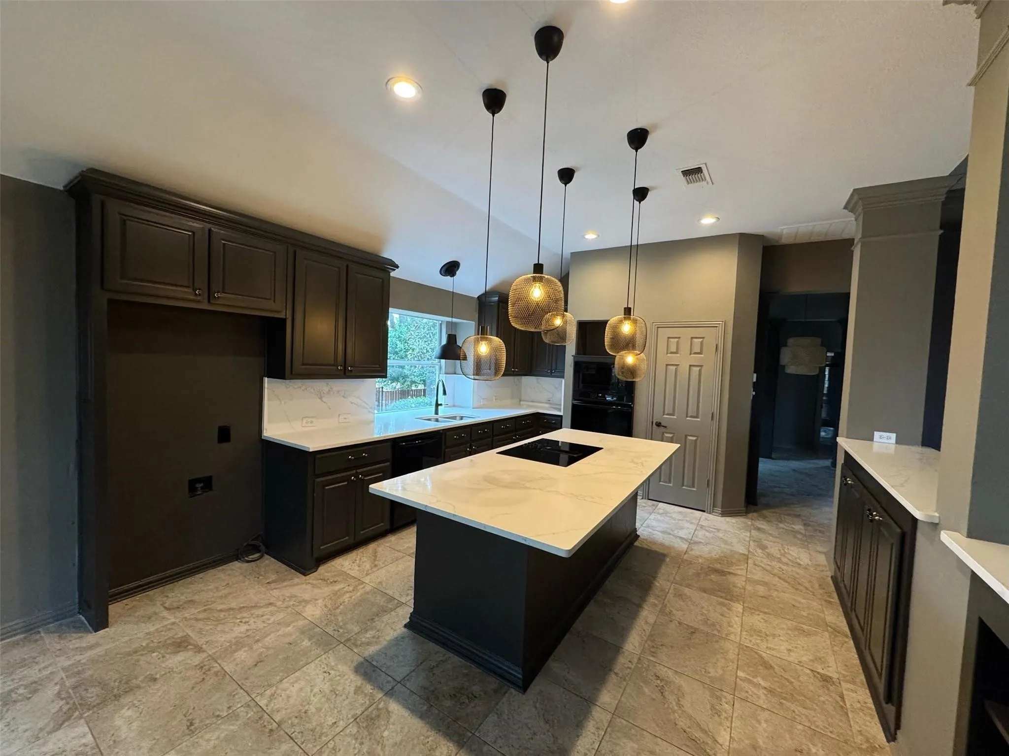 The fully renovated kitchen features a center island with electric cooktop, updated appliances, gorgeous lighting, and a breakfast bar overlooking the living room.