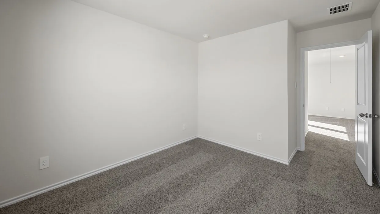 Spacious bedroom with neutral wall finishes, neutral carpet flooring, and natural light from the entry door