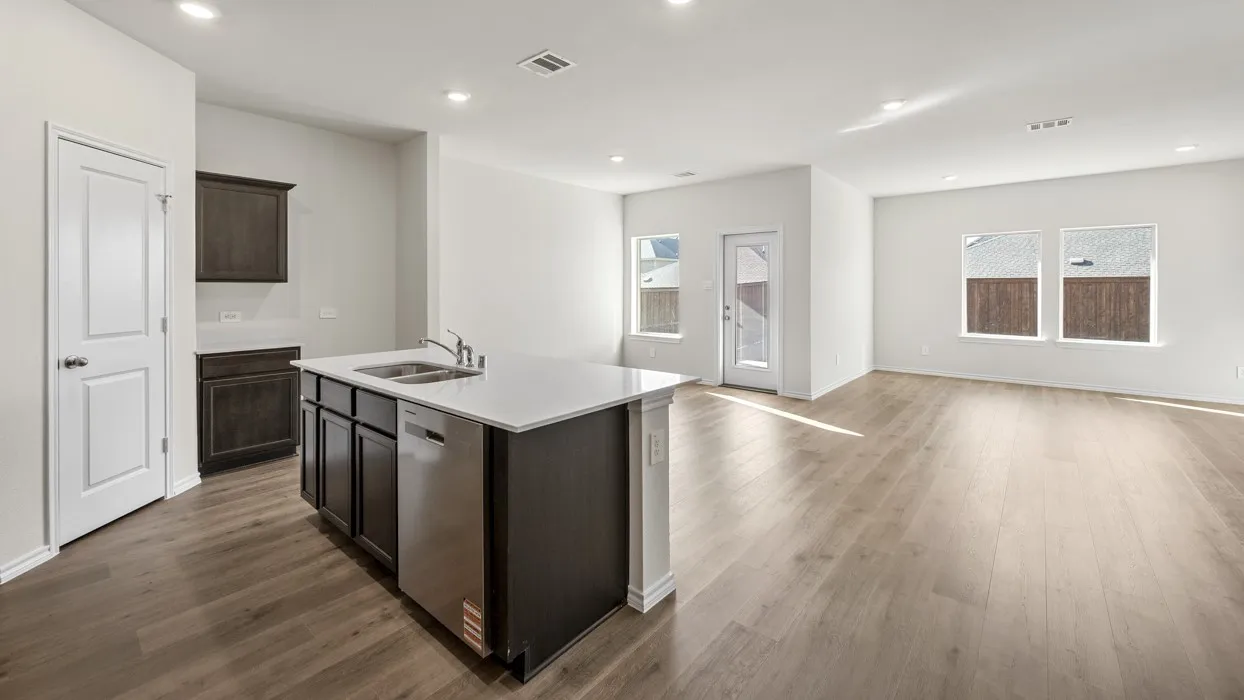 Open-concept layout featuring wood-finish flooring, recessed lighting, a kitchen island with integrated sink, stainless steel dishwasher, and white countertops
