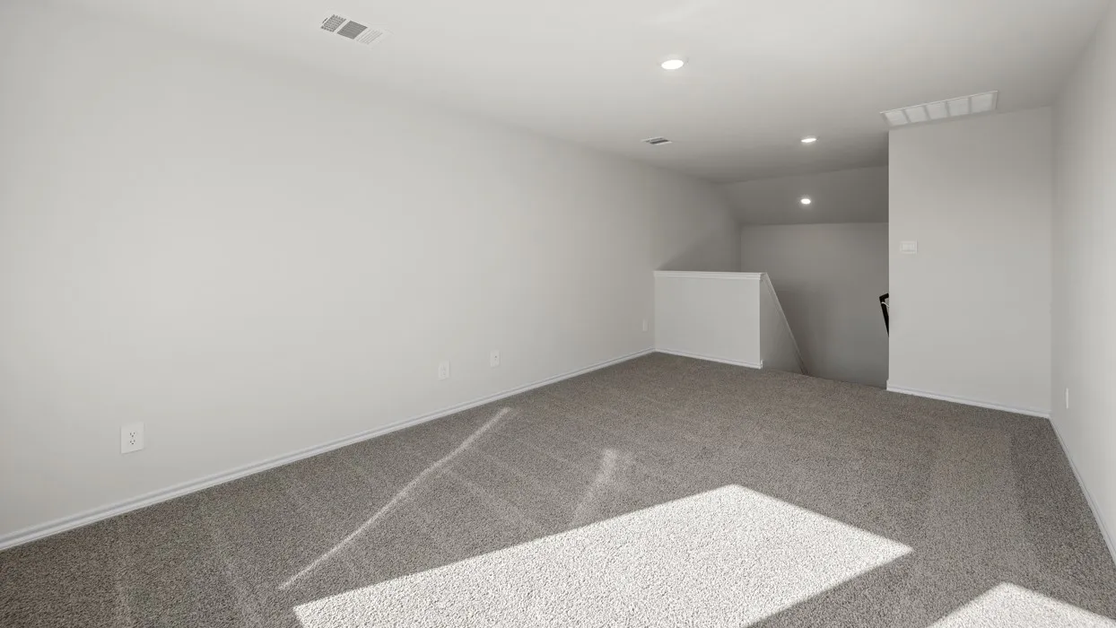 Spacious room with light gray carpeting, neutral-toned walls, recessed lighting, and a built-in half-wall partition