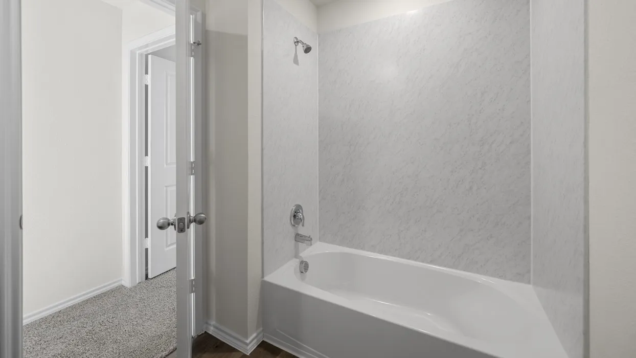 White bathtub with a gray-patterned shower surround and chrome fixtures