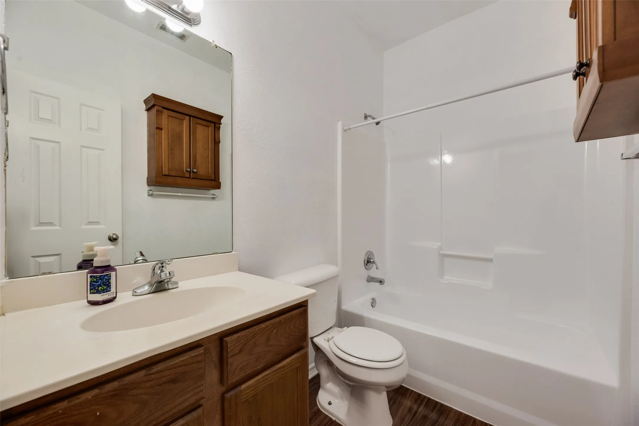 Vanity with integrated sink, wood-finish cabinetry, and a framed mirror