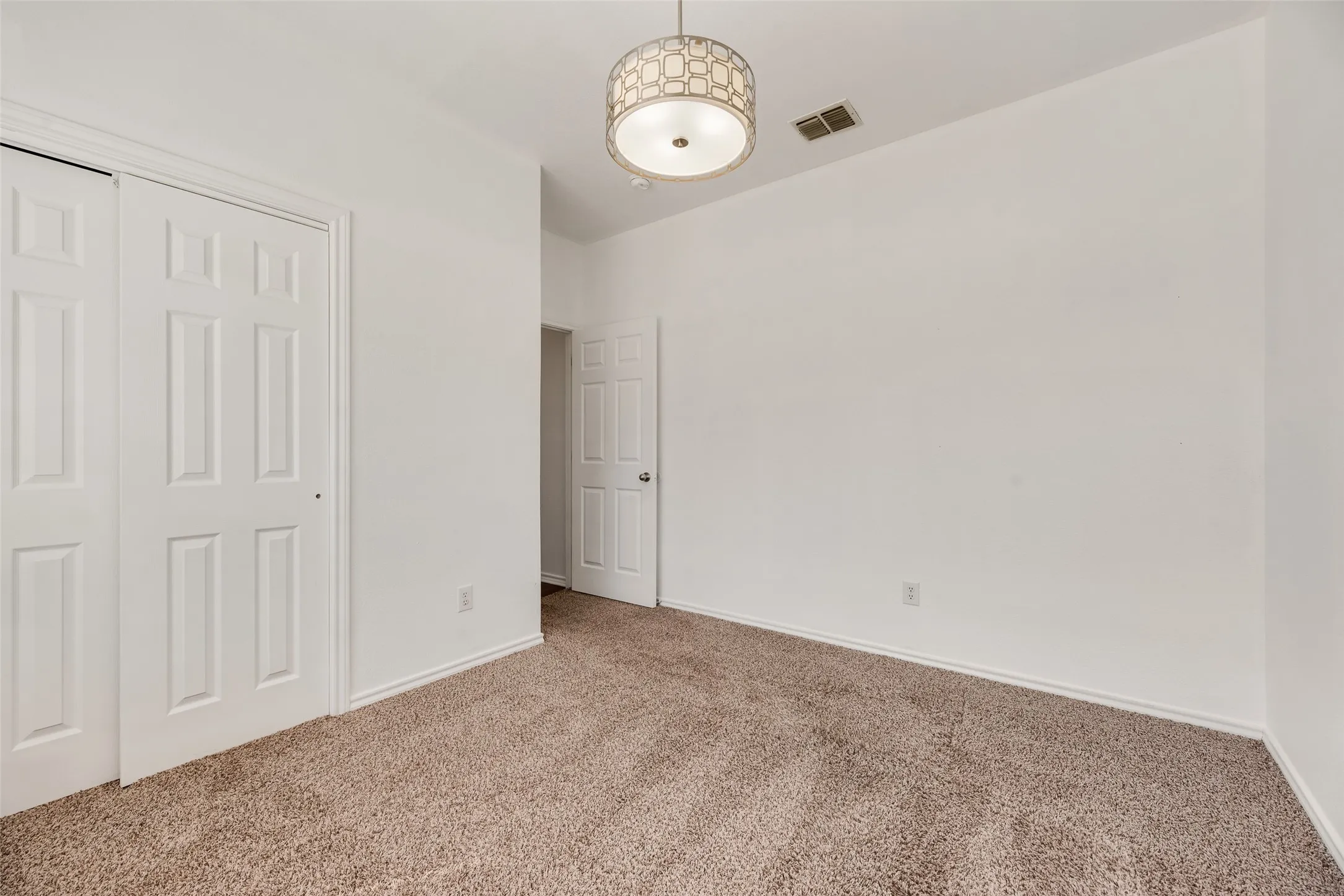 Neutral-toned carpeting, white walls, and a decorative ceiling light fixture