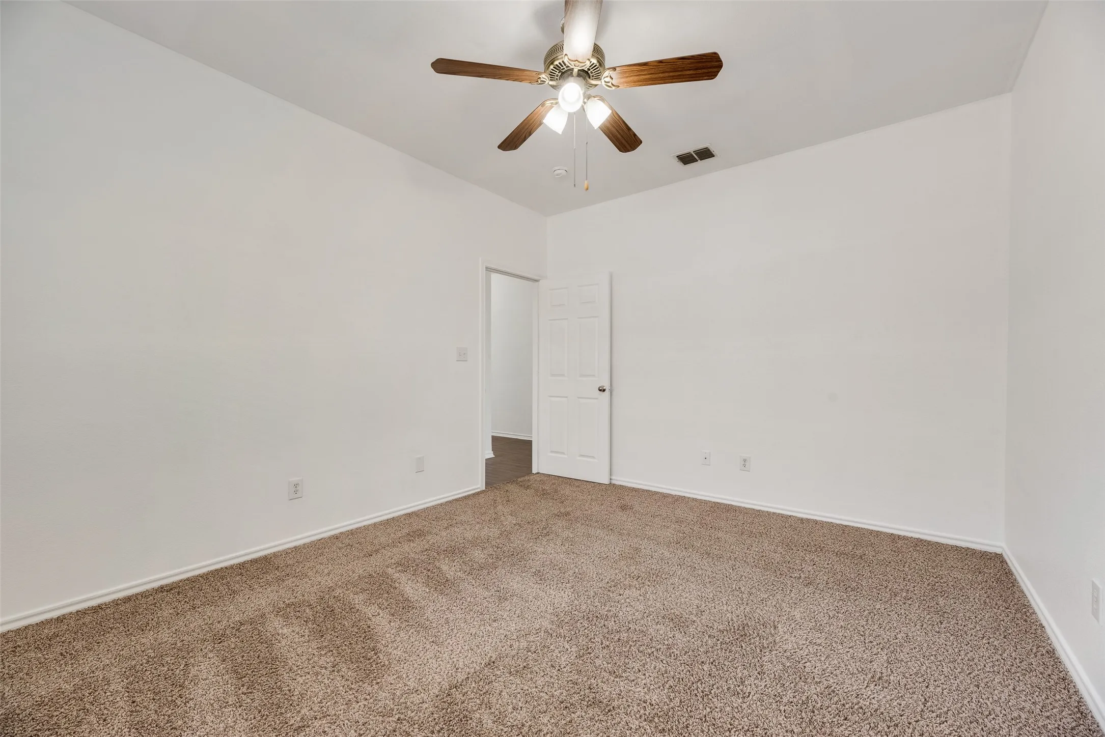 Plush carpeted flooring, neutral wall tones, and a ceiling fan with light fixture