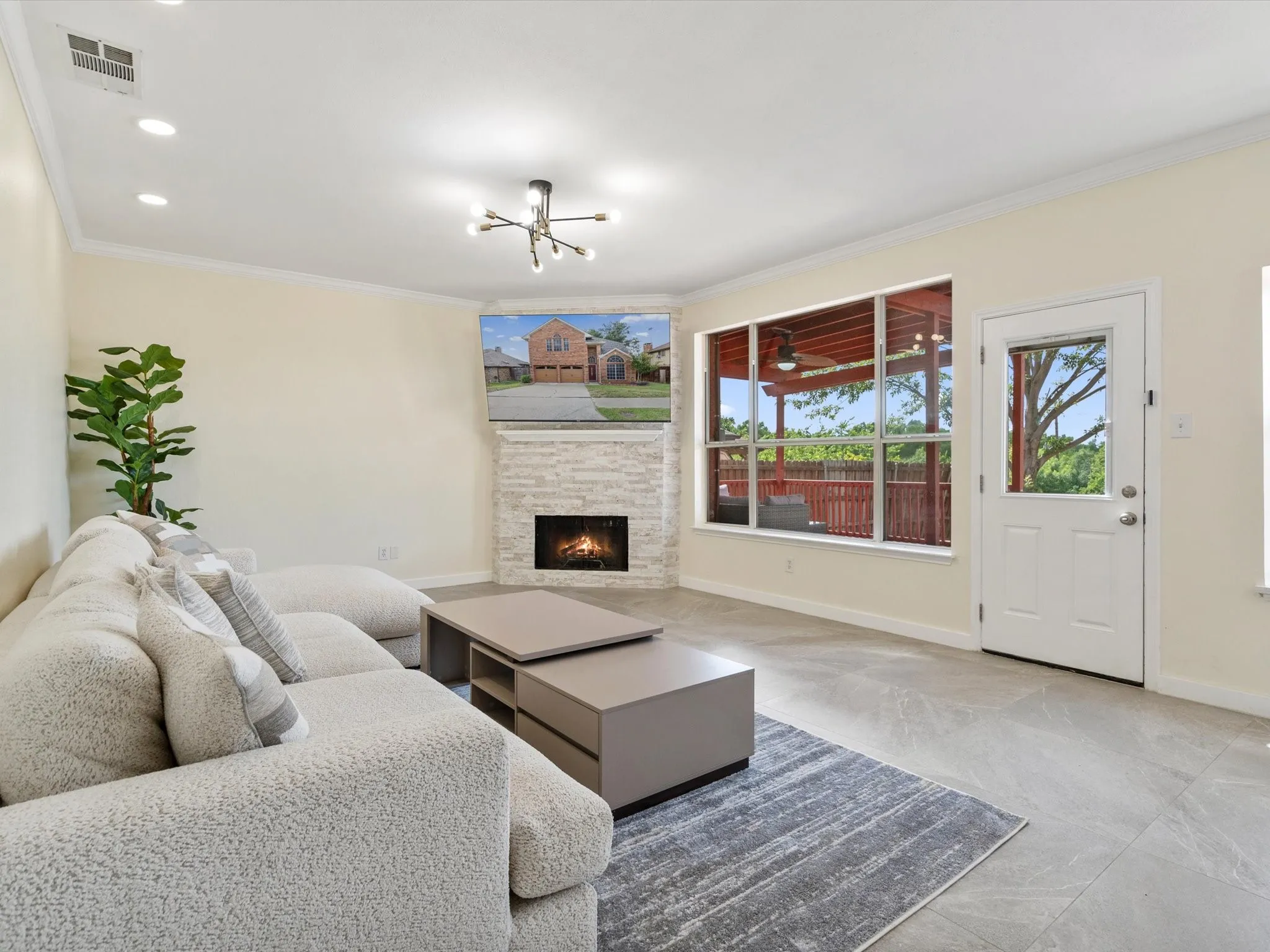 Living area with crown molding, a stone fireplace, a chandelier, and recessed lighting