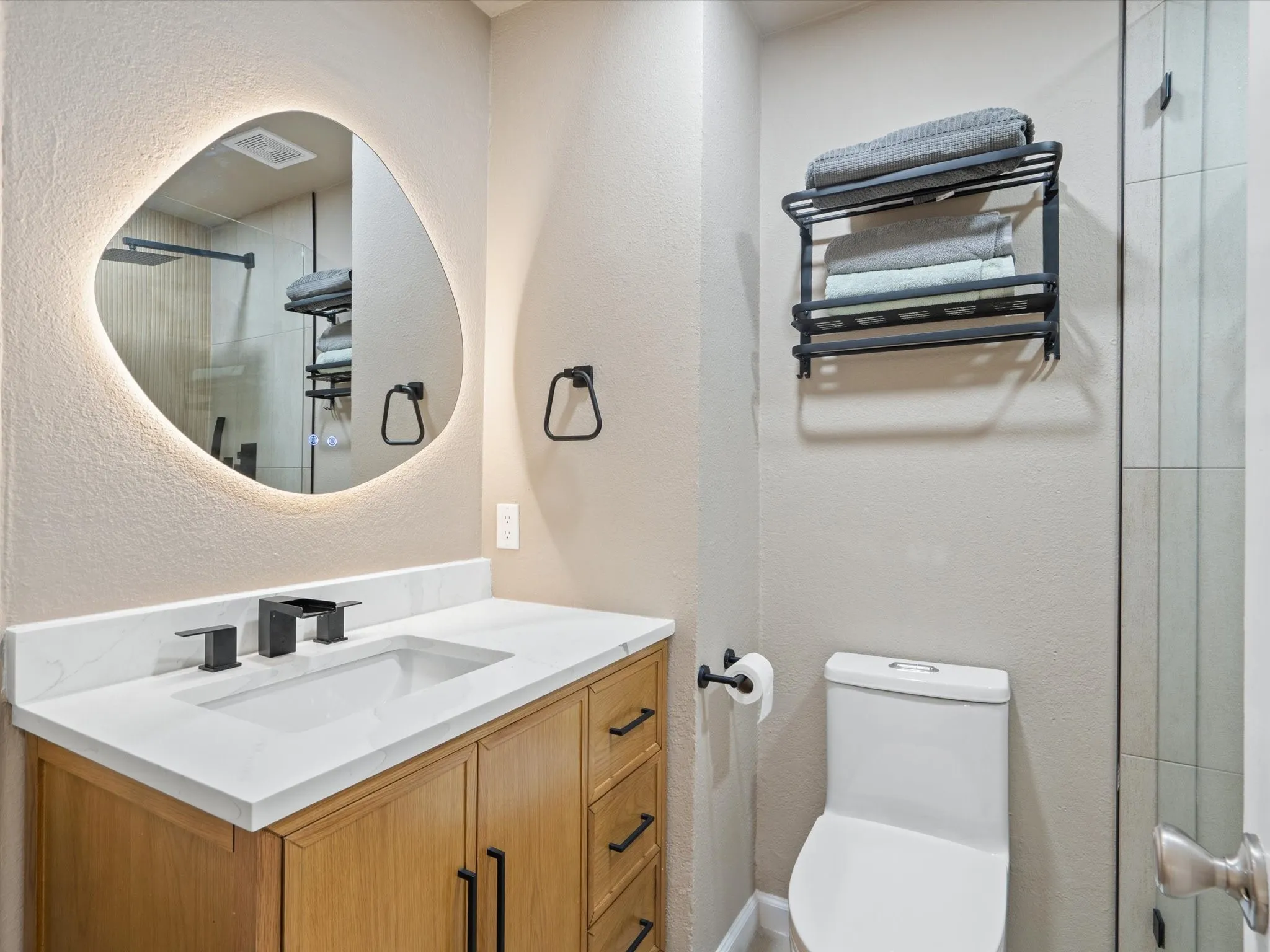 Bathroom with a textured wall, vanity, and a shower