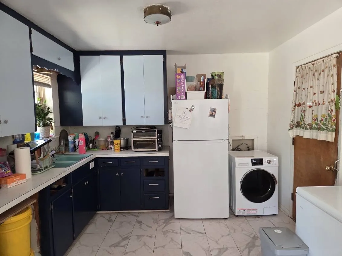 White ceiling with flush-mount lighting, two-tone cabinetry with upper and lower units, white countertops, and light-toned tile flooring