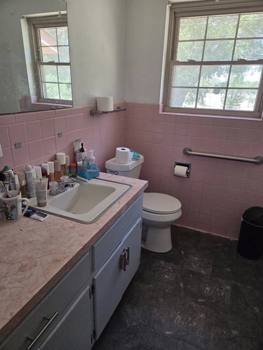 Bathroom featuring pink ceramic wall tiling and a light pink countertop with an integrated sink