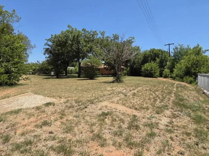 Expansive lot featuring mature trees and a gravel pad