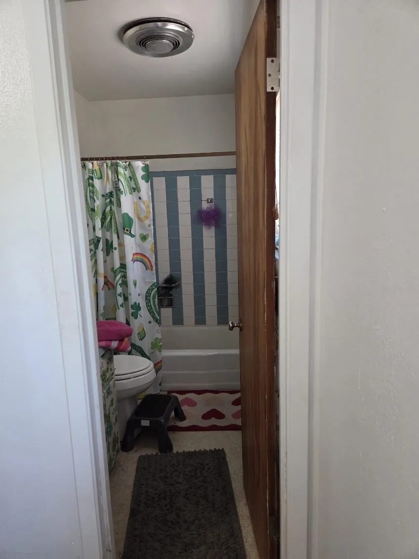 White bathtub with striped wall tiling and a ceiling-mounted light fixture