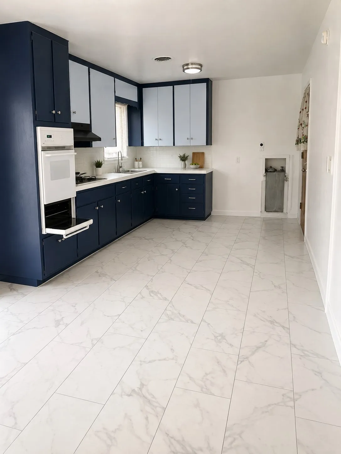 Spacious kitchen featuring two-tone cabinetry, white countertops, built-in wall oven, white subway tile backsplash, and wide plank tile flooring