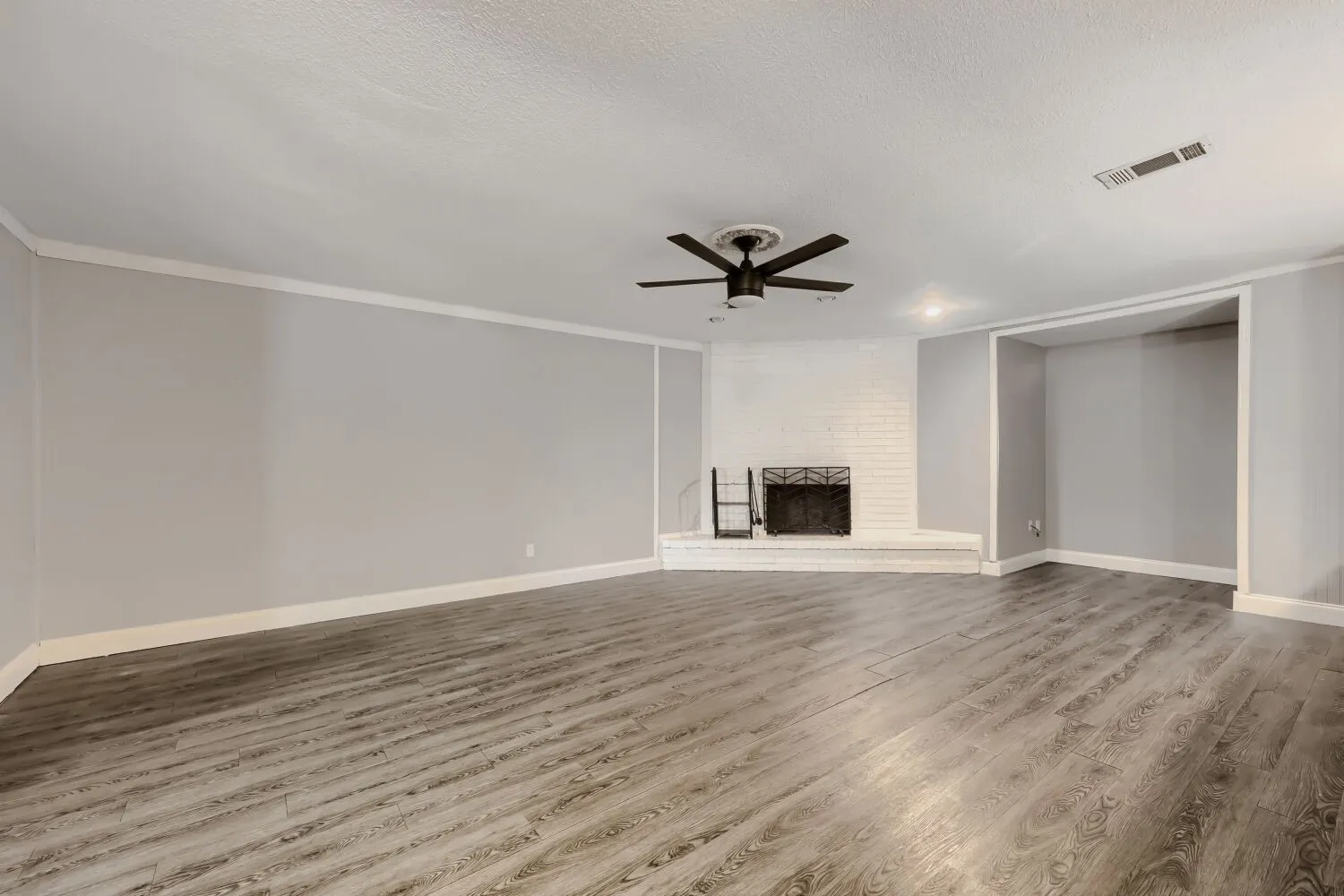 Spacious living area featuring wood-finish flooring, a white brick fireplace, recessed lighting, and a ceiling fan