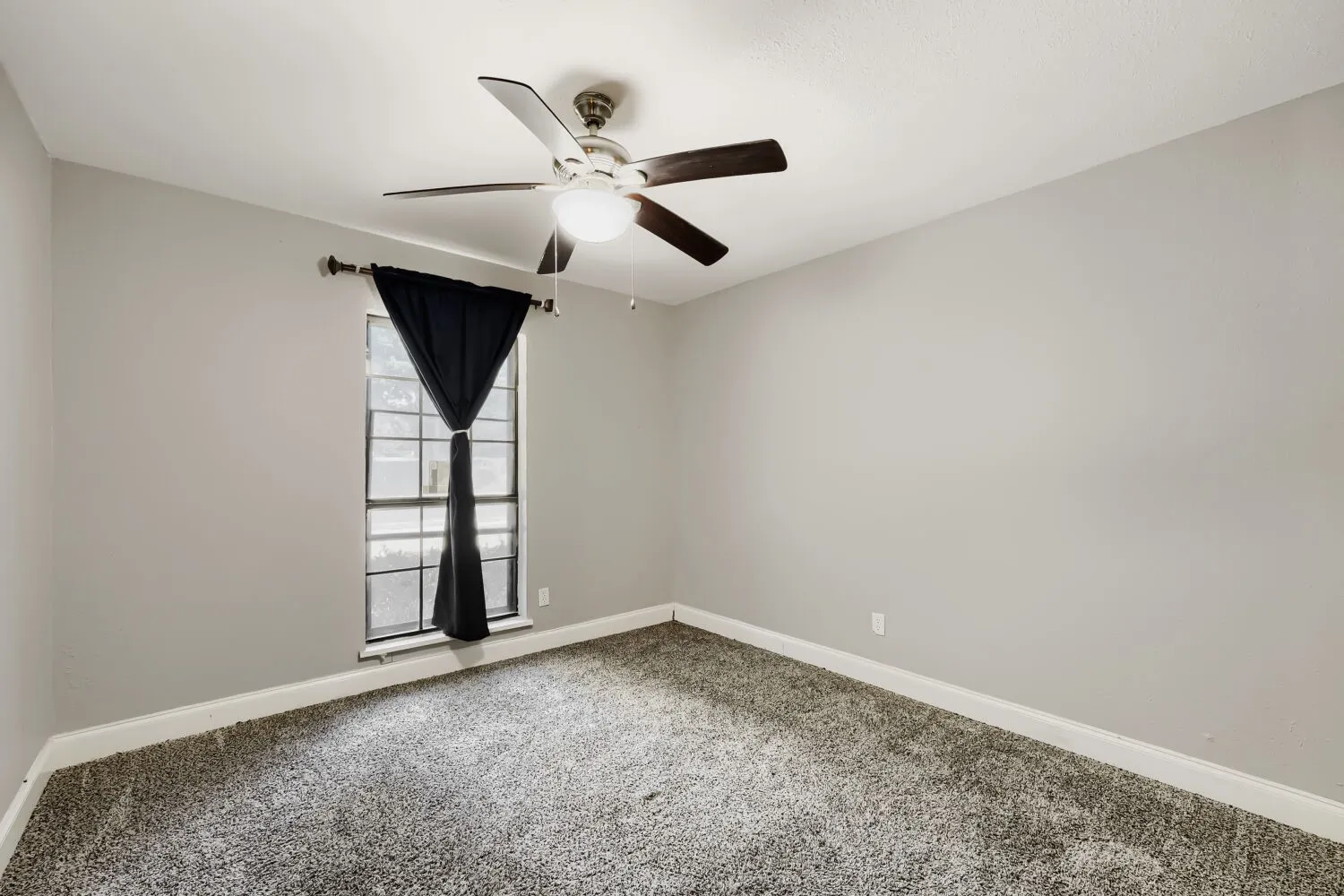Carpeted flooring, neutral wall tones, ceiling fan with integrated lighting, and a window with trim