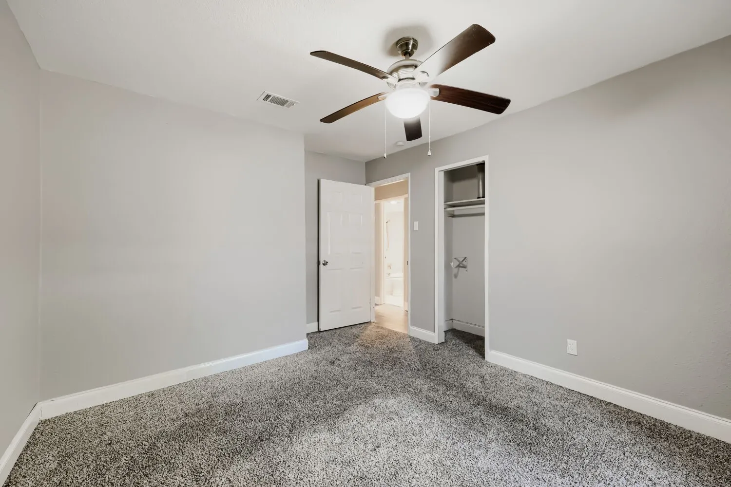 Recessed closet with a clothes rod, ceiling fan with integrated lighting, textured carpeting, and white trim