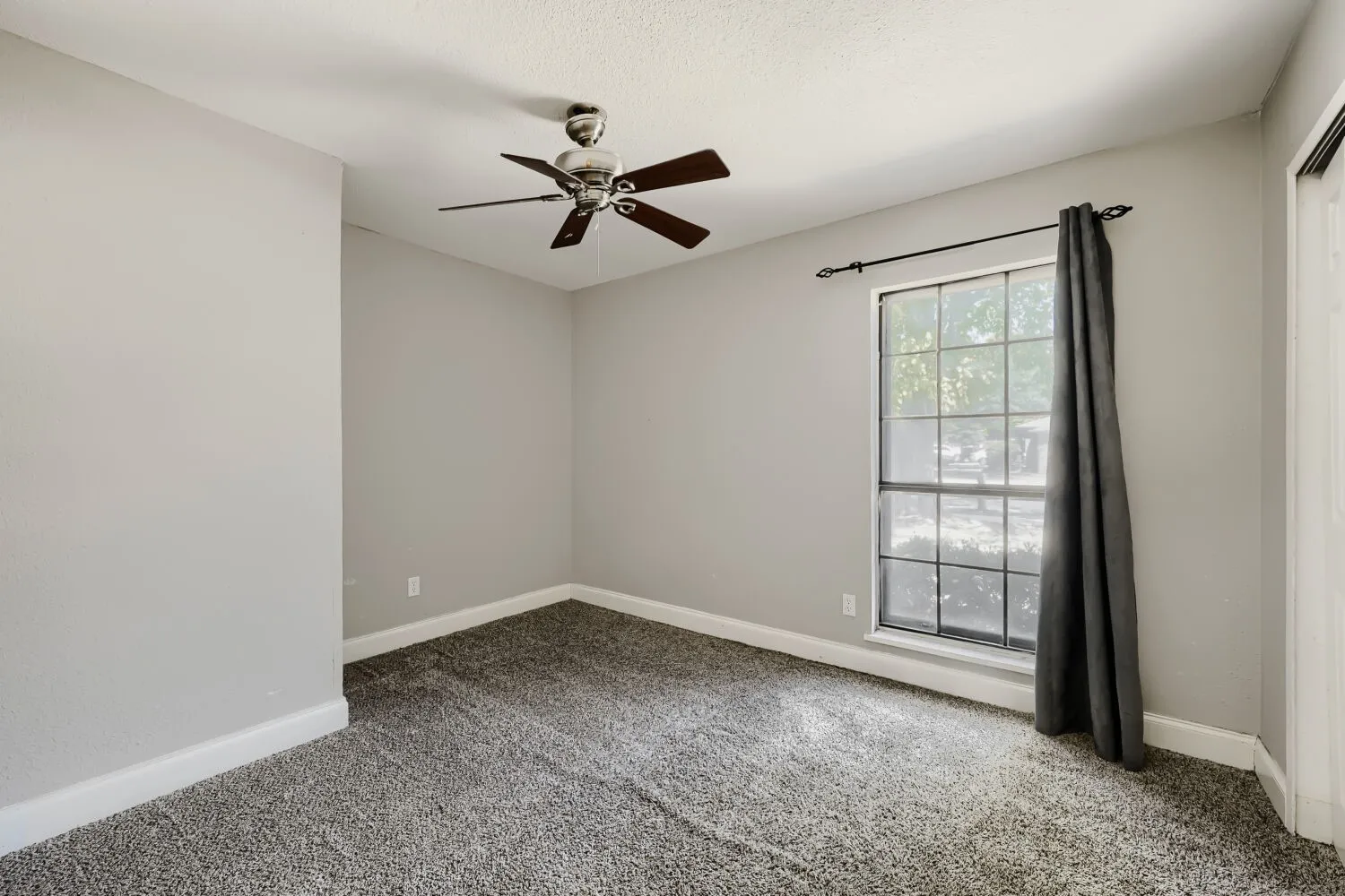 Charming brick home featuring a spacious two-car garage with a light-colored overhead door, concrete driveway, and mature shade trees framing the front elevation