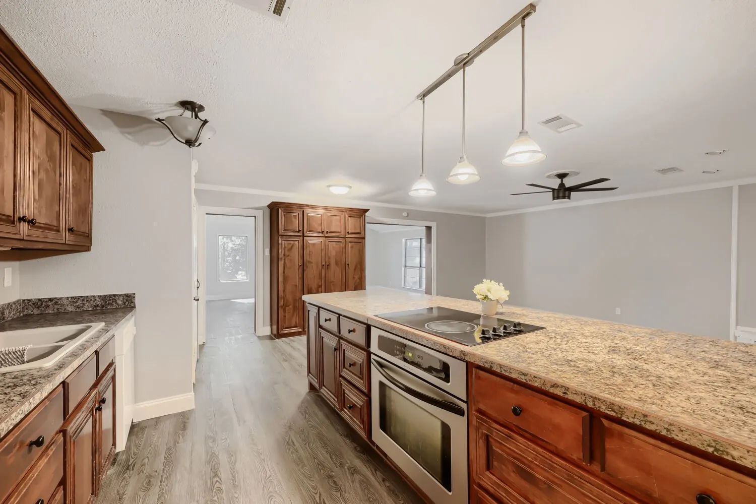 Kitchen featuring wood-finish cabinetry, stone-finish countertops, and an integrated oven with cooktop