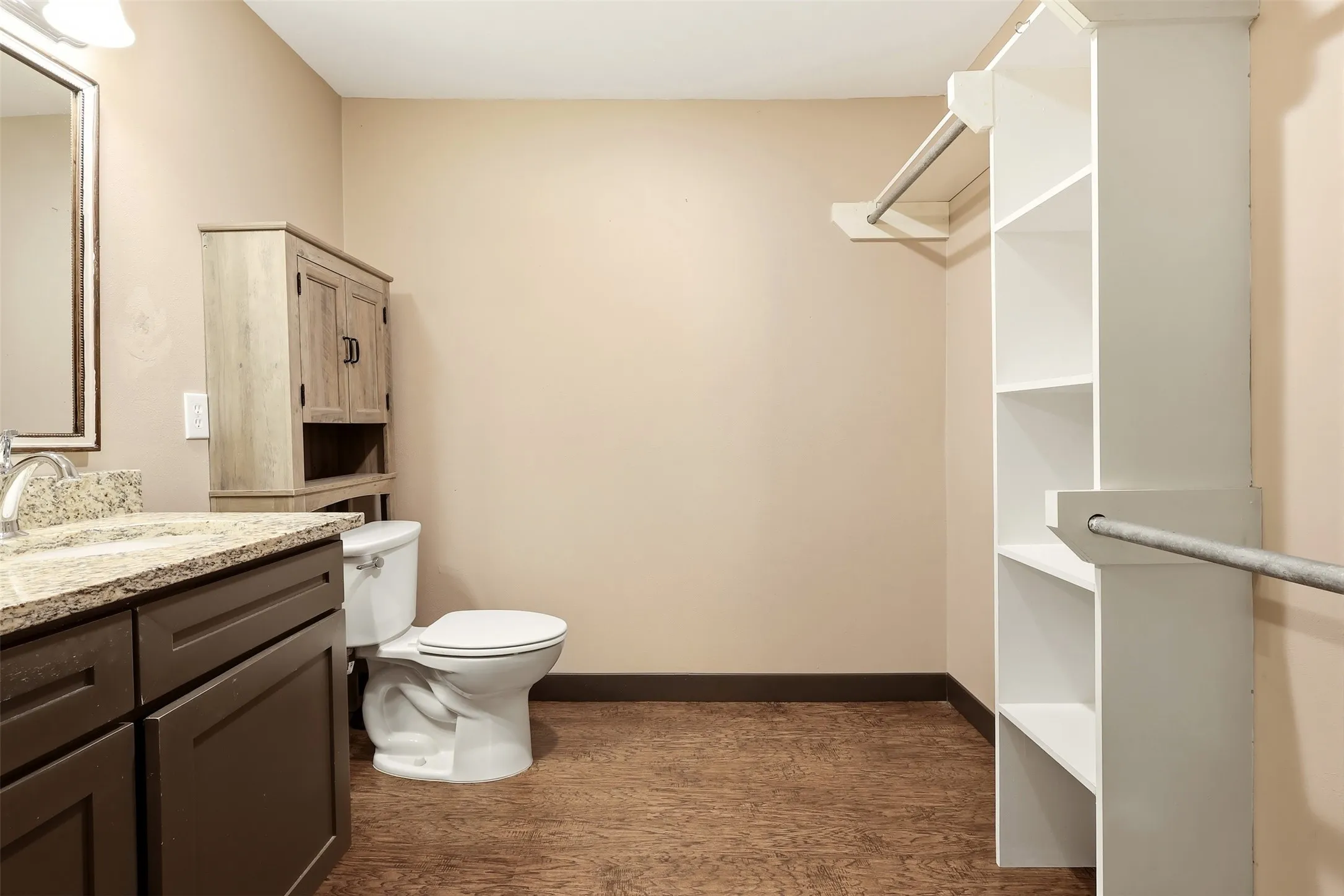 Bathroom featuring a dark wood-finish vanity with a light-toned countertop, a toilet, and an additional storage cabinet