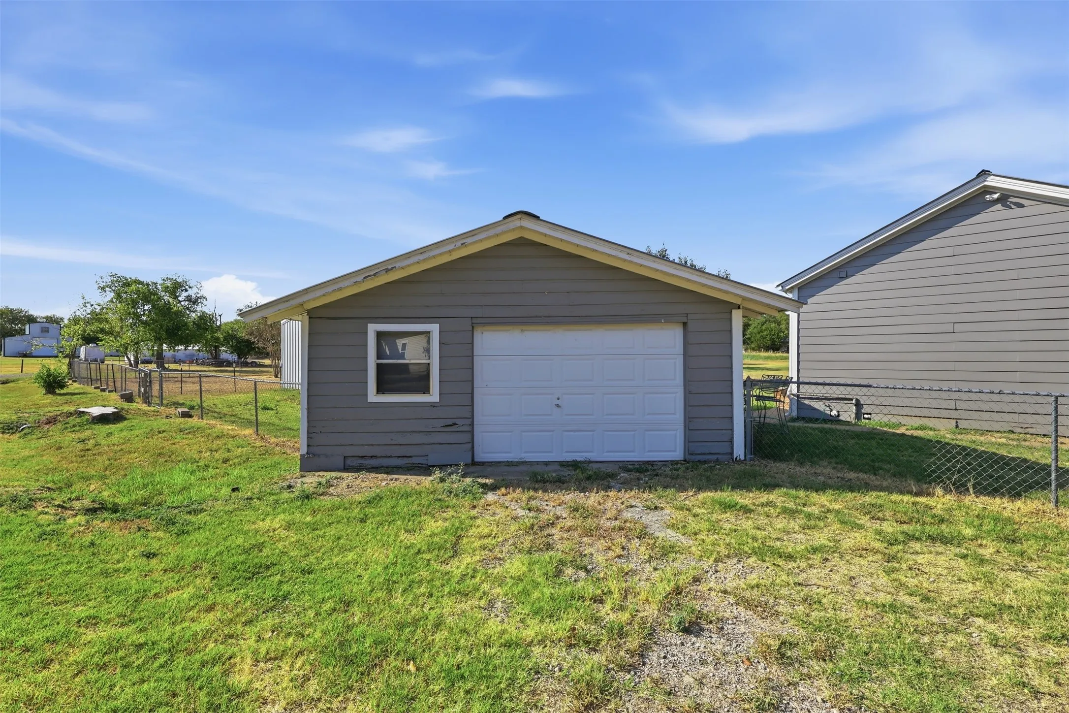 Detached garage with horizontal siding, a white overhead door, and a single window