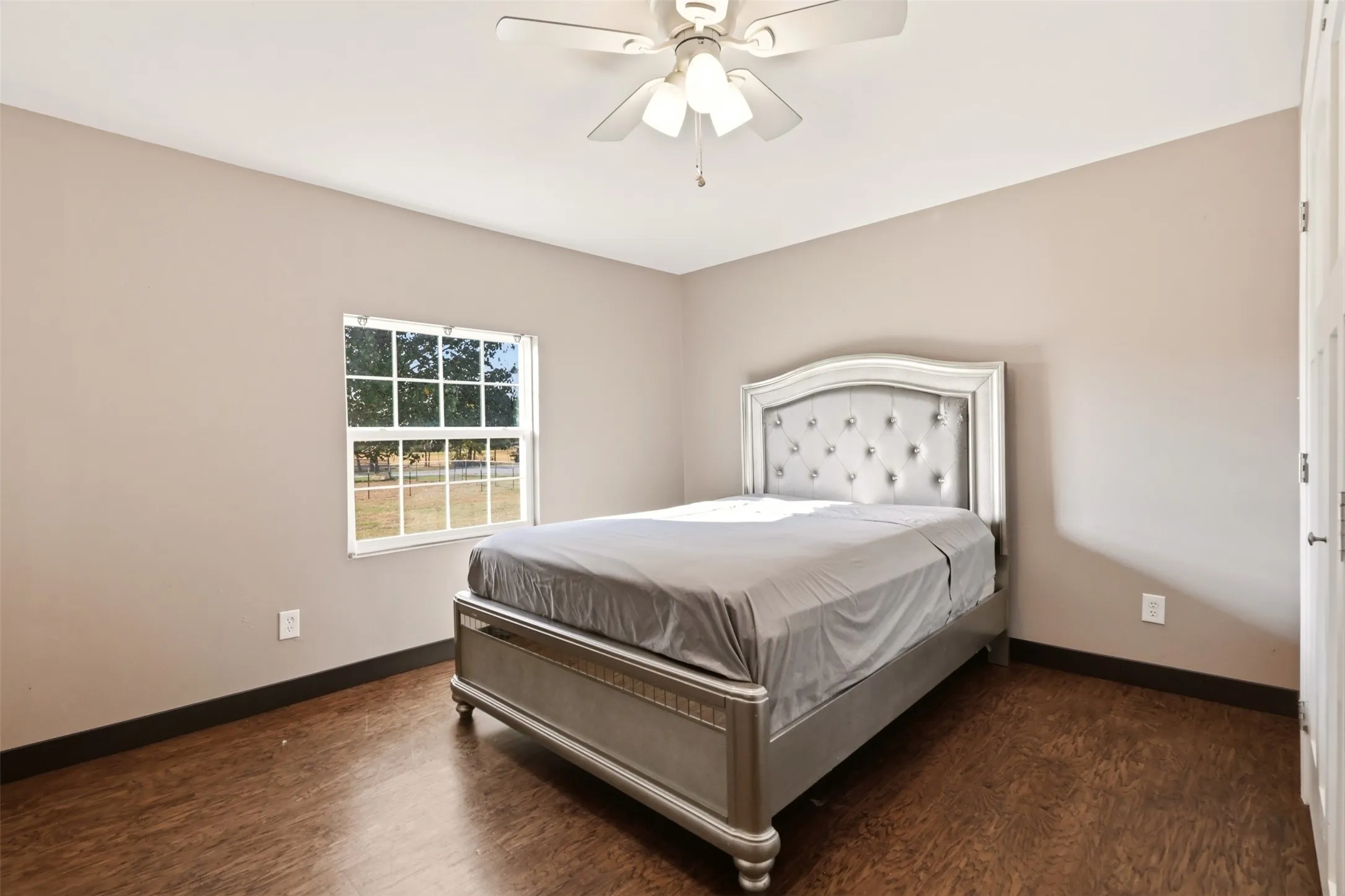 Wood-finish flooring with a neutral wall color, white trim, and a ceiling fan with light fixture