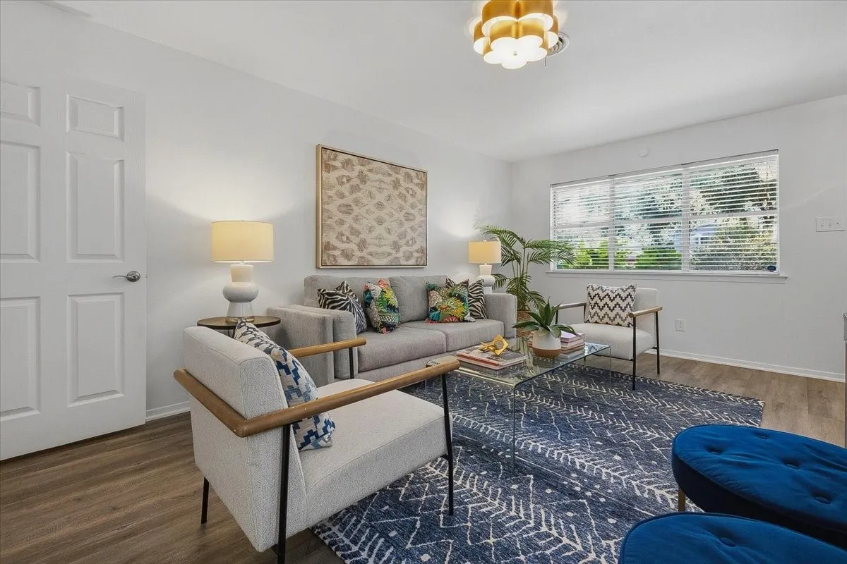 Decorative lighting, wood-finish flooring, and a large window with blinds