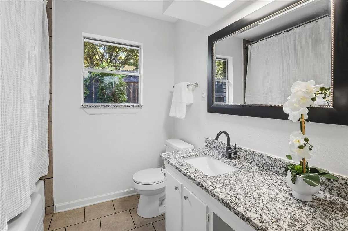 Vanity with a granite countertop, undermount sink, and matte black faucet