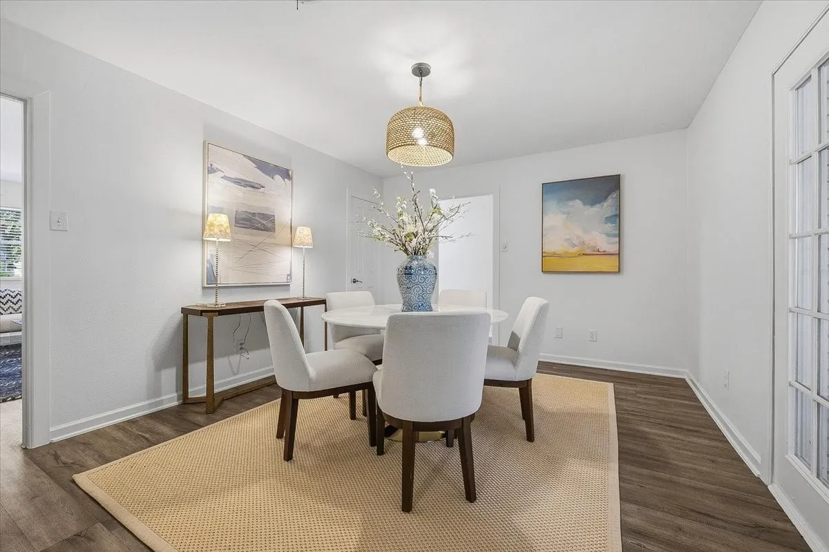 Elegant dining room showcasing a round white table, white upholstered chairs with wood legs, and warm brass pendant lighting