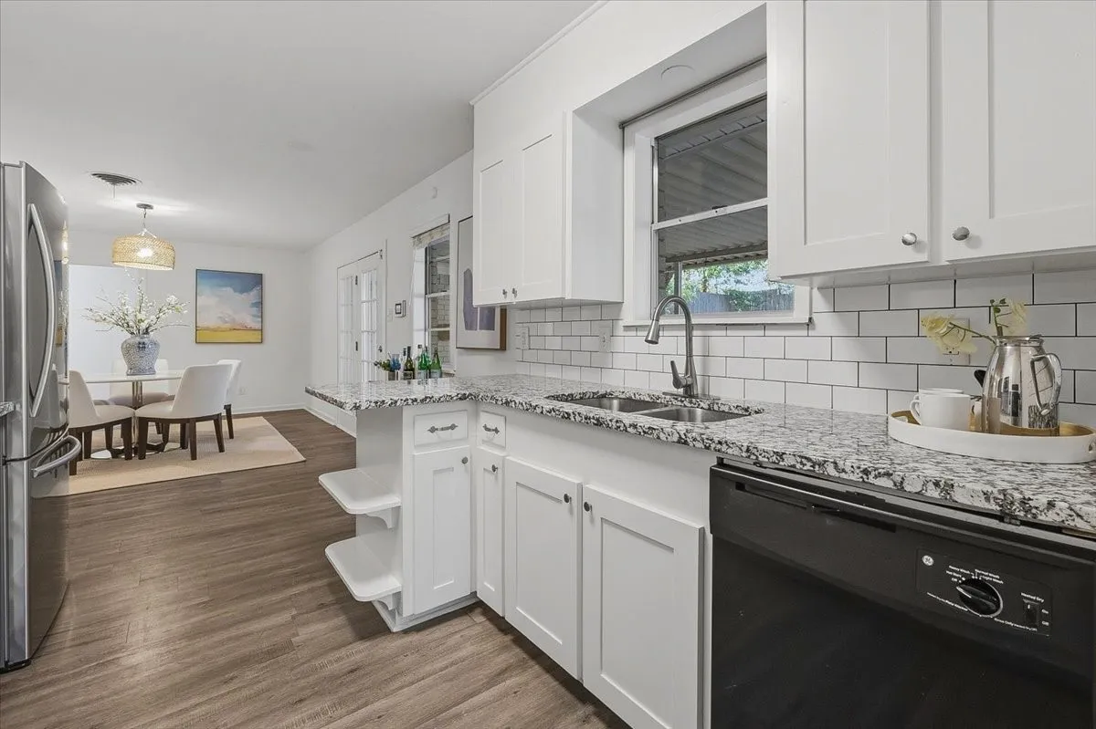 Kitchen with white shaker cabinetry, speckled countertops, a stainless steel double basin sink, and a white subway tile backsplash