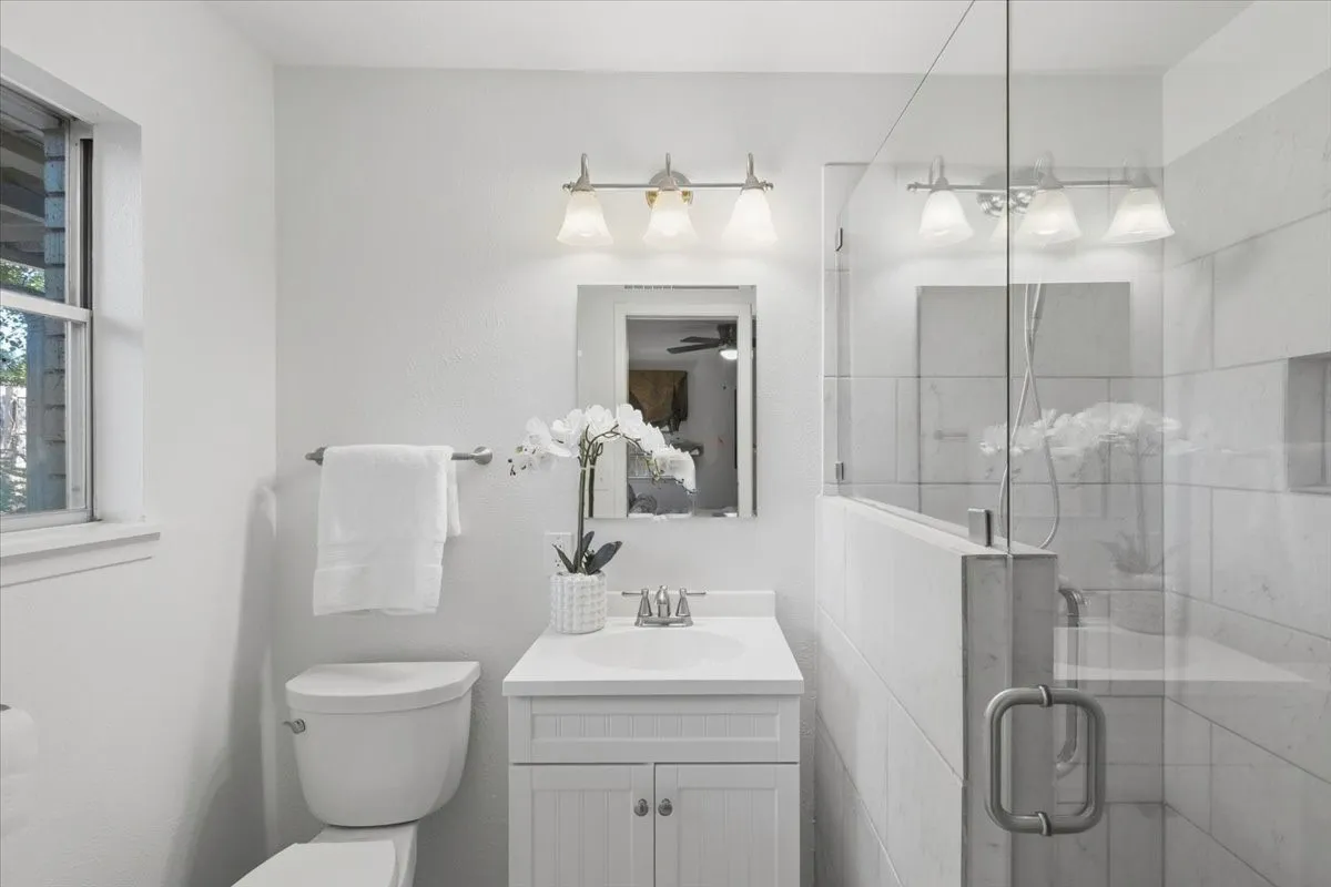 Spa-inspired bathroom featuring a frameless glass-enclosed shower with subway tile surround, floating vanity with dual cabinet storage and rectangular sink, polished chrome fixtures, and dual vanity lighting