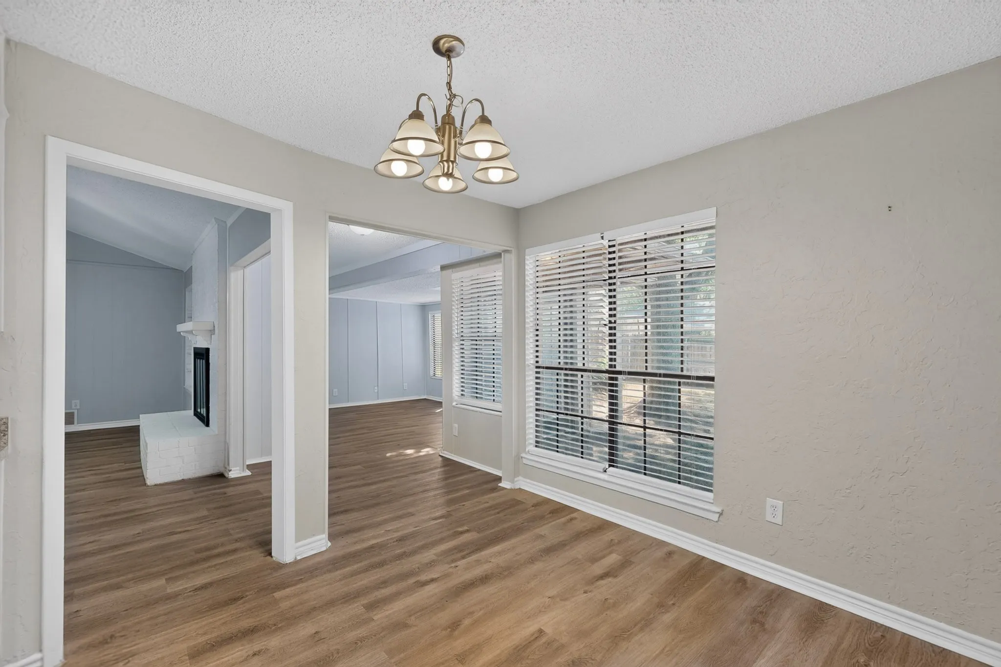 Formal dining area featuring wood-finish flooring, a multi-light chandelier, and large windows with blinds