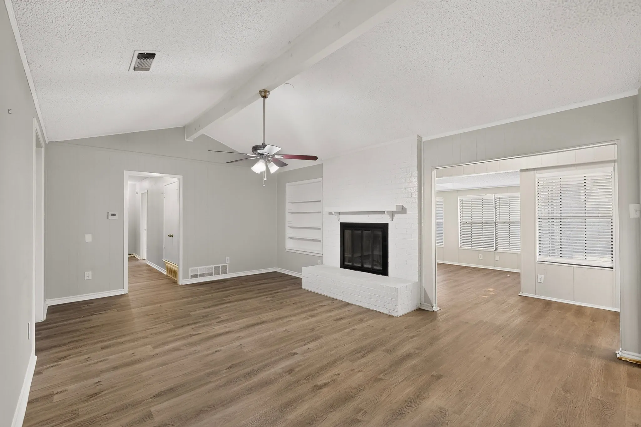 Wood-finish flooring throughout, a vaulted ceiling with exposed beams, and a ceiling fan