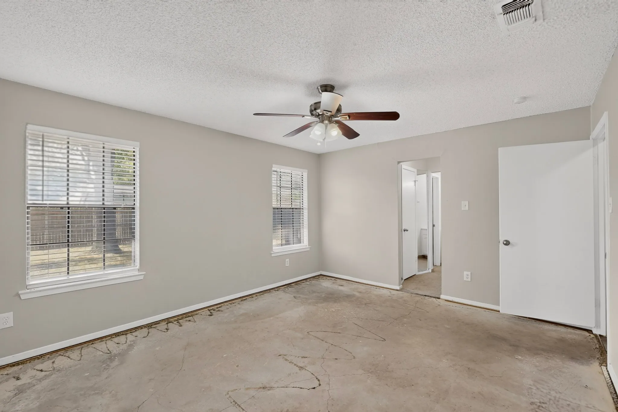 Room featuring light gray painted walls, a ceiling fan with light fixture, and two windows with white blinds