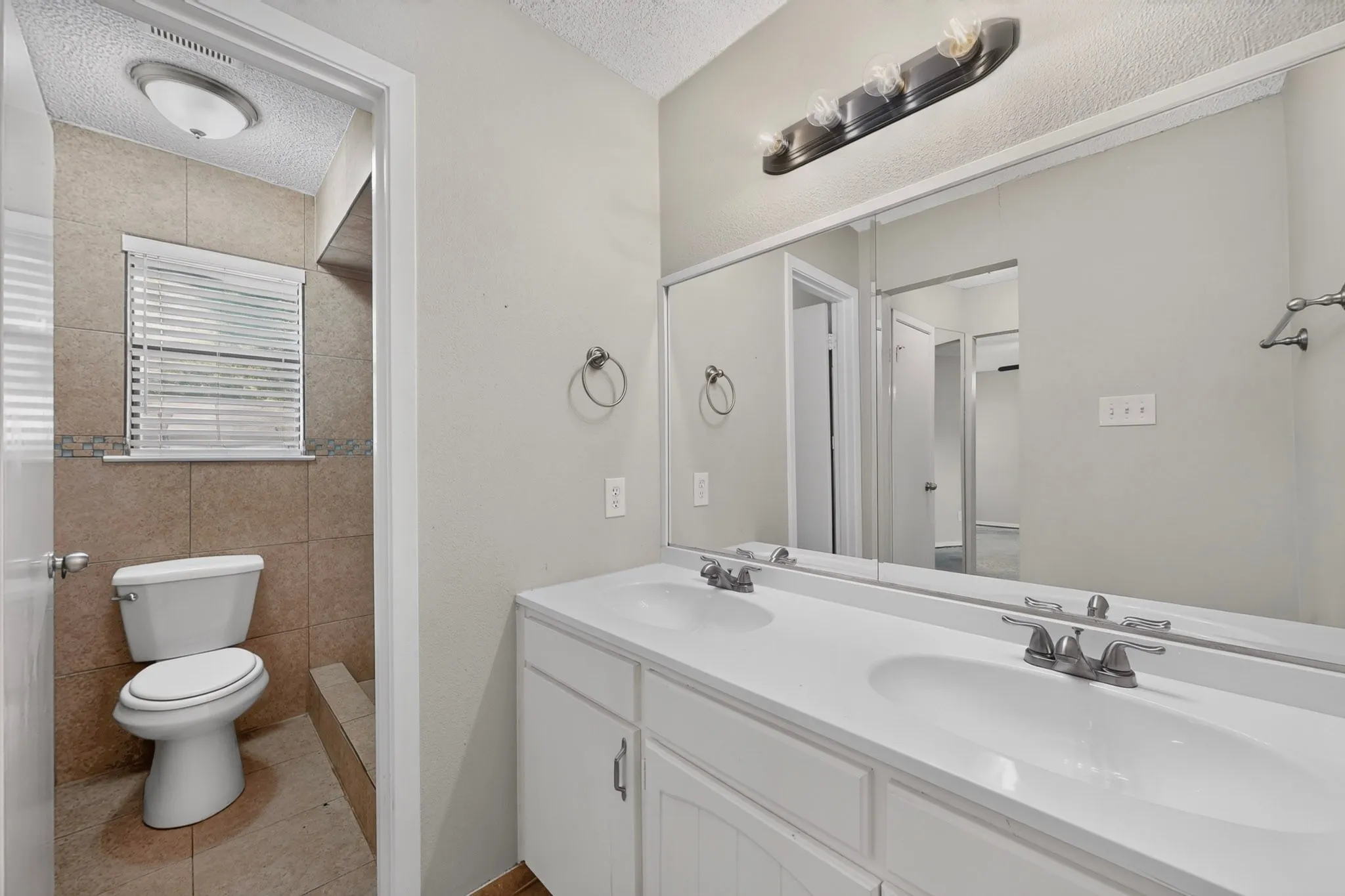 Dual vanity with undermount sinks, an expansive wall mirror, and a three-light fixture