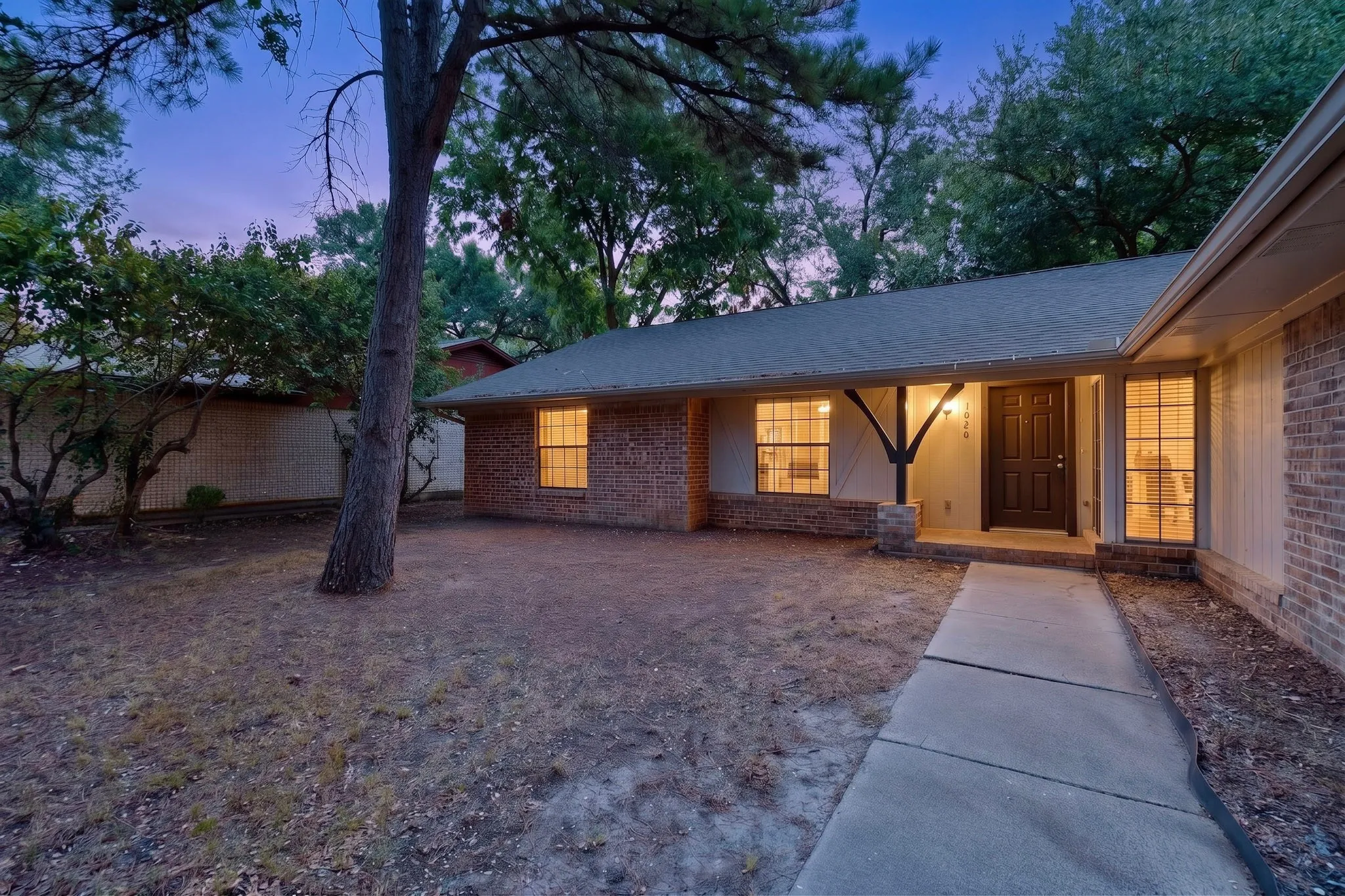 Brick exterior with a covered entry, dark wood-finish front door, and multiple front-facing windows