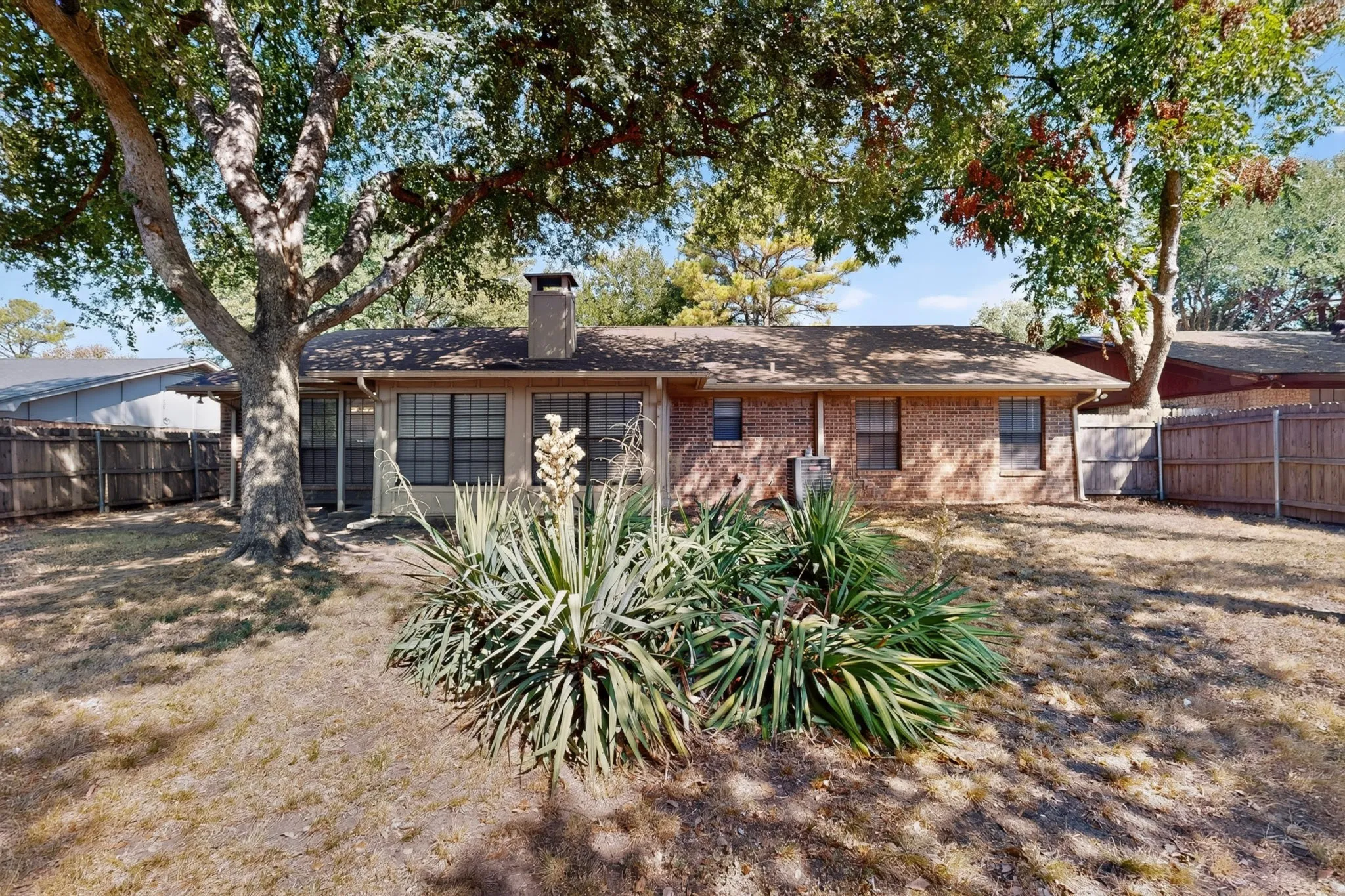 Brick exterior with multiple windows and a shingle roof