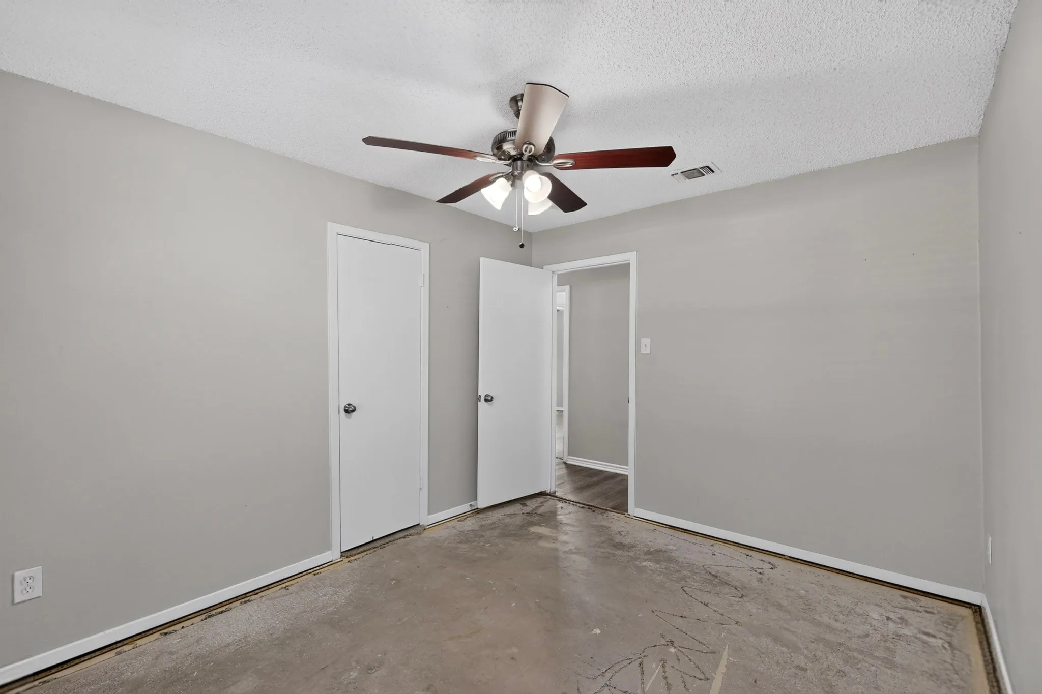 Ceiling fan with light fixture, two interior doors with round hardware, and light gray wall paint