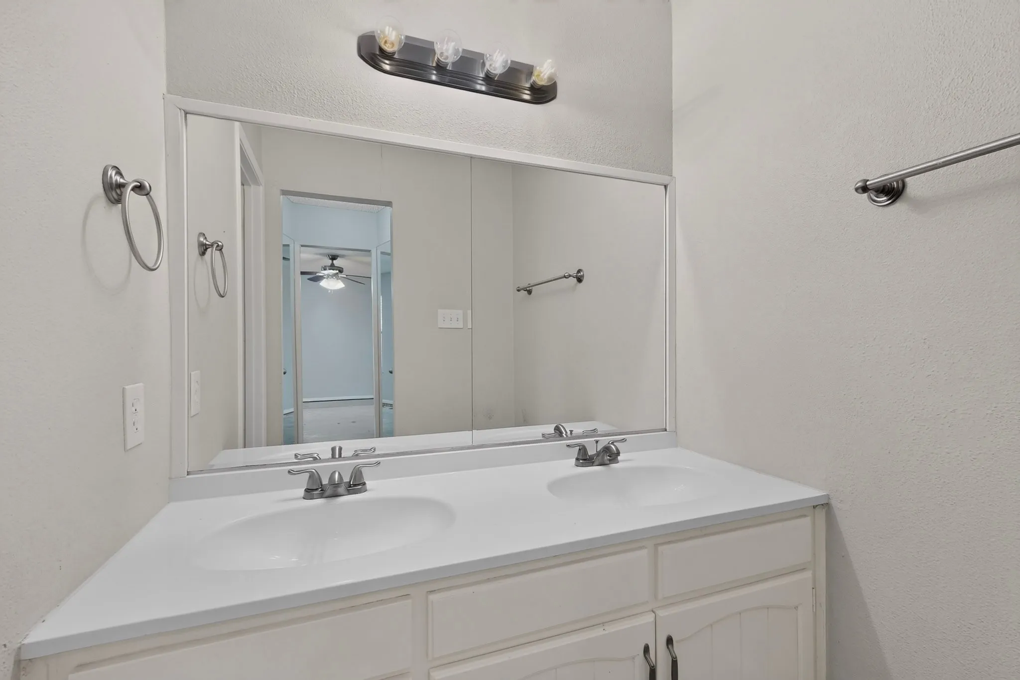 Dual basin vanity with integrated white sinks, brushed nickel faucets, and a full-width mirror