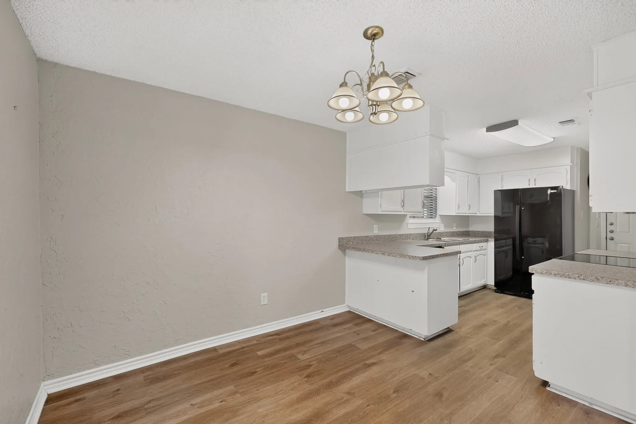 Wood-finish flooring, white cabinetry, integrated sink, and a black appliance suite
