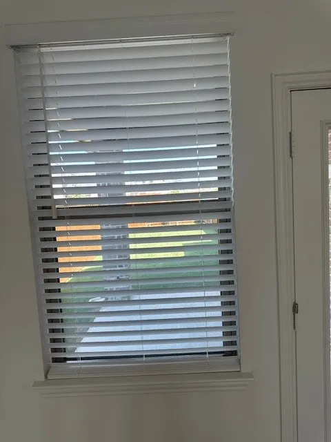 Window featuring white horizontal blinds, a white window frame, and a decorative window sill
