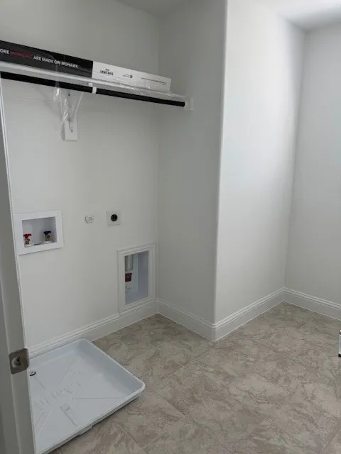 Utility room with a built-in shelf, hanging rod, and tile flooring
