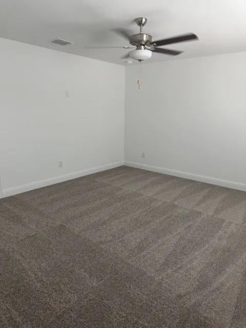 Neutral tone carpeting, white walls, and a ceiling fan with integrated lighting