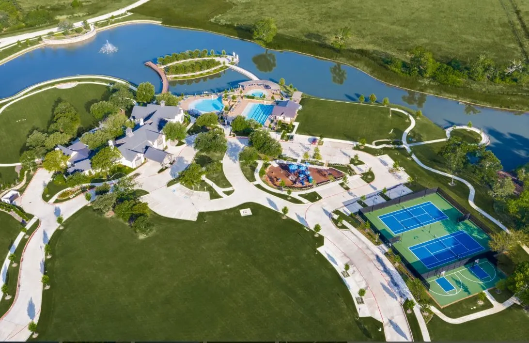 Expansive property featuring a large lake with a central fountain, multiple swimming pools, tennis courts, and a basketball court