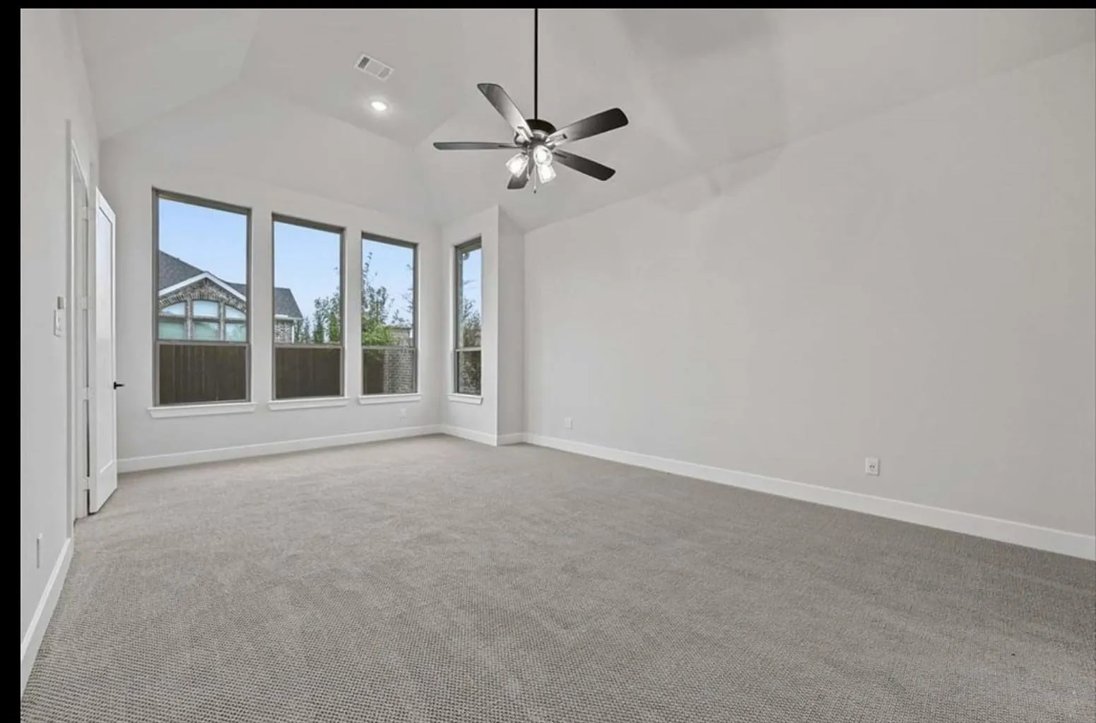 Vaulted ceiling with recessed lighting and ceiling fan, neutral carpeting, and multiple windows
