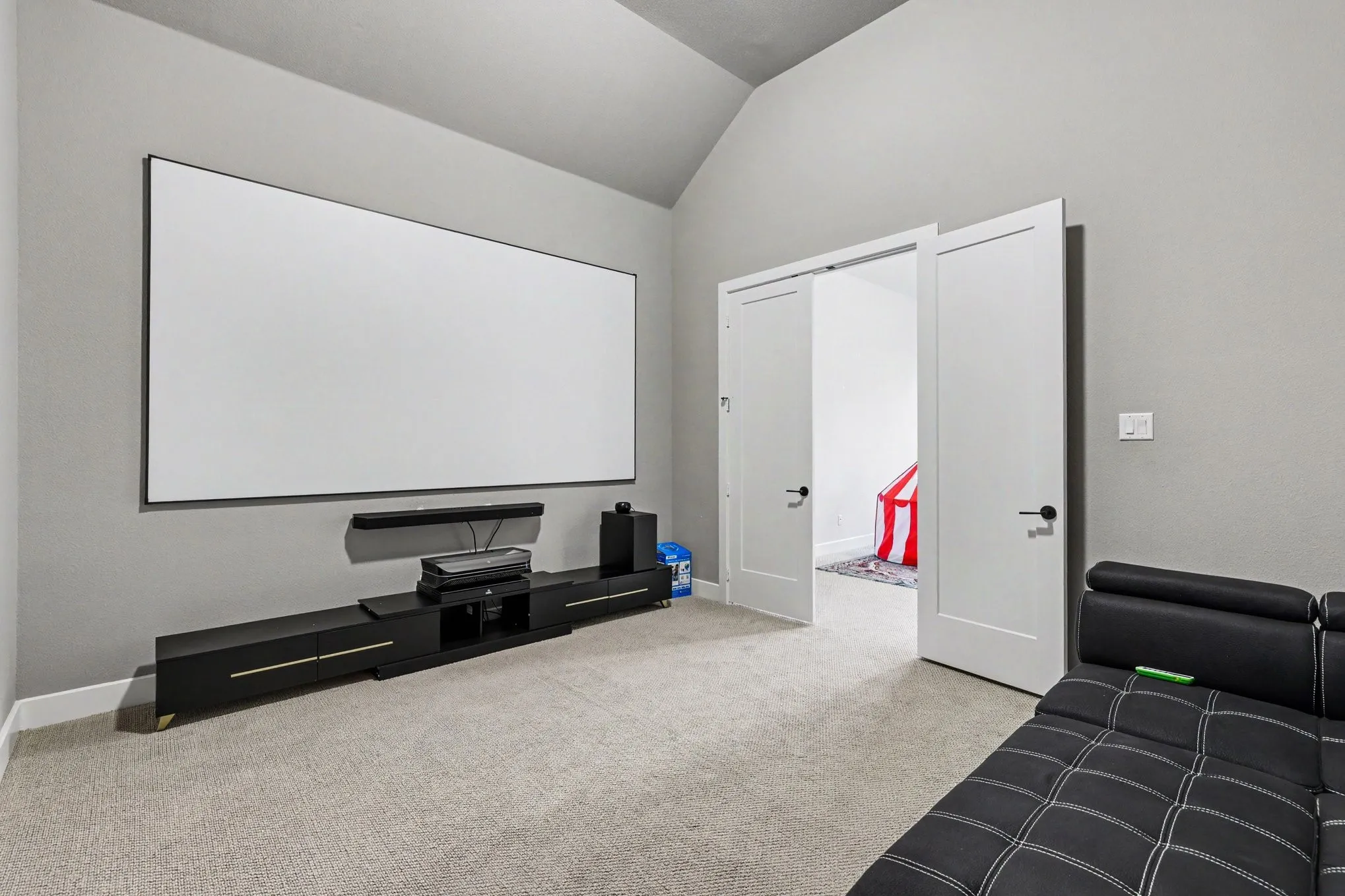 Vaulted ceiling accentuates this media room featuring a large projection screen and a built-in media console