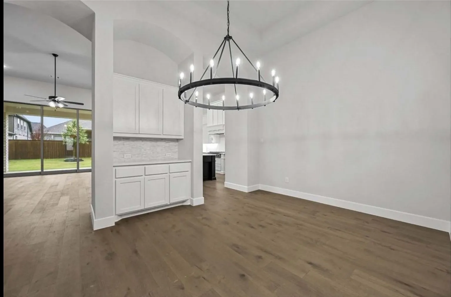 Wood-finish flooring, recessed built-in cabinetry with tiled backsplash, and an arched​​‌​​​​‌​​‌‌​‌‌​​​‌‌​‌​‌​‌​​​‌​​ entryway
